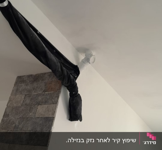 צינור מכוסה בבד שחור על קיר לבן
